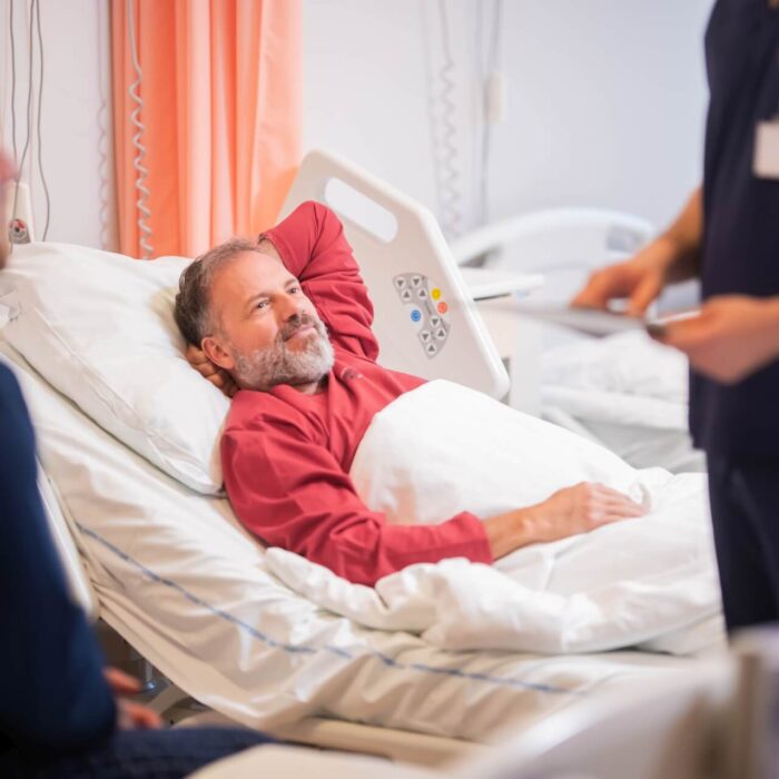 Pacjent leżący w szpitalny łóżku obok lekarze